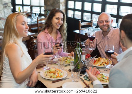 Positive happy young people enjoying food and smiling at tavern