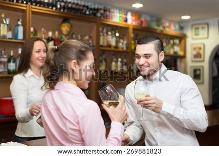 Happy young smiling couple having a date with wine at bar. Focus on guy