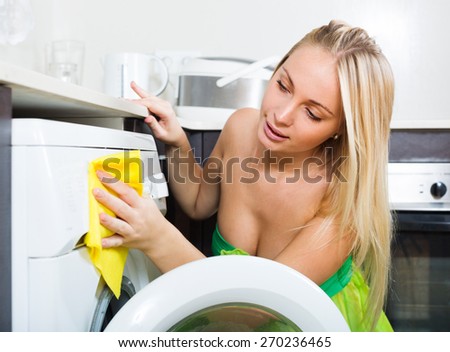 woman cleaning washing machine at home kitchen