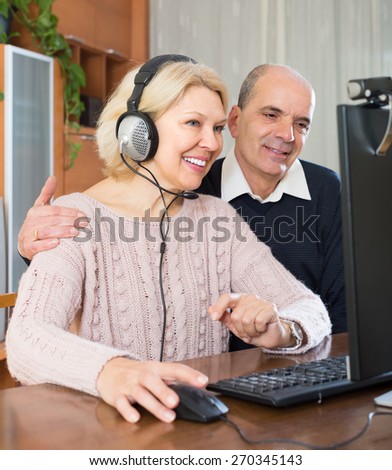 Smiling senior couple using PC for video calls at home