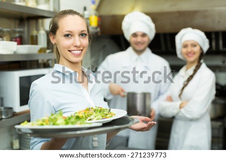 Team of chefs and female waiter at restaurant kitchen