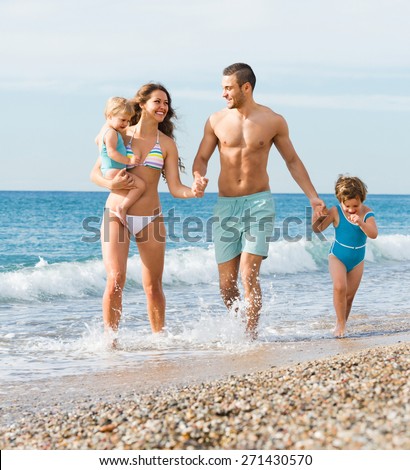 Happy young parents with two children resting at sea shore in vacation