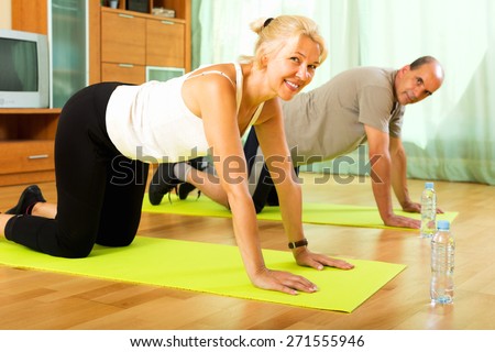 Smiling pensioners doing morning exercises indoor, warm tone