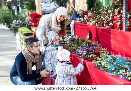 Smiling married couple with two children choosing Christmas star flower at market.