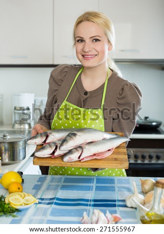 Smiling russian woman with fish at home kitchen
