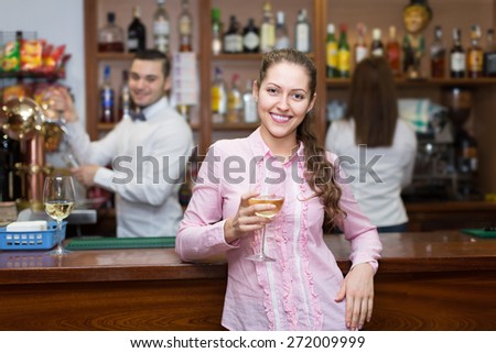 Young attractive girl standing at bar with glass of wine