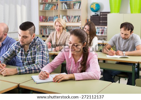 Attentive adult students writing down summary in classroom