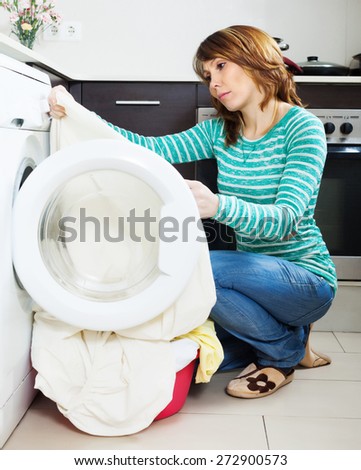 Unhappy  housewife with  clothes near washing machine at  home