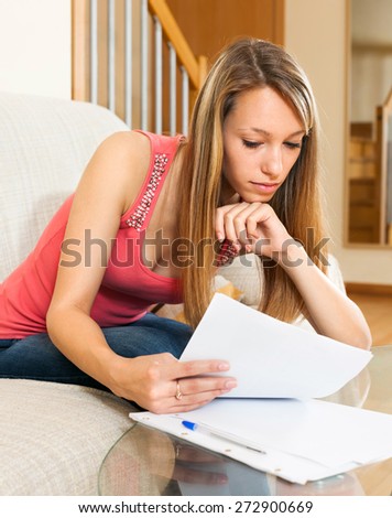 Young student on the sofa reading notes and preparing for the exam at home