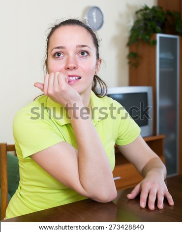 Agitated girl deep in thought biting fingers at home
