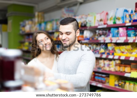 happy russian customers standing near shelves with canned goods at shop