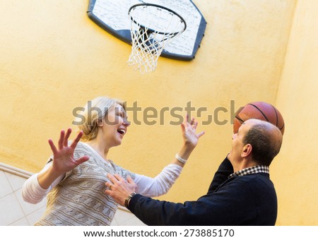 Positive senior couple throwing the ball into basket