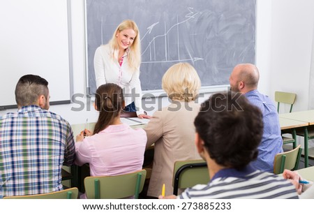 Adult students with attractive smiling female teacher at training session for employees