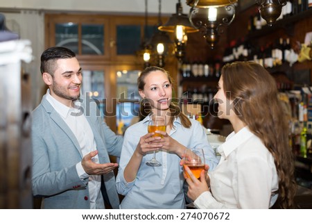 Positive smiling girls flirting with man at bar of restaurant