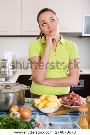 Confused young long-haired housewife thinking what to prepare for dinner