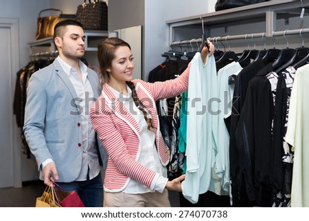 Young couple choosing new apparel in clothing store. Focus on girl