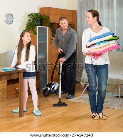 Happy family of three cleaning at home all together. Focus on girl