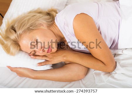 Blonde middle-aged woman sleeping in bed at home