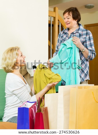 Smiling pensioner bragging with new blouse in front of happy friend