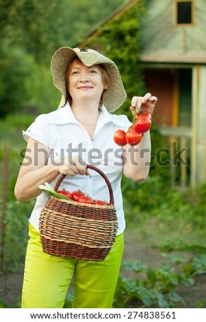 Happy mature woman with basket of harvested vegetables