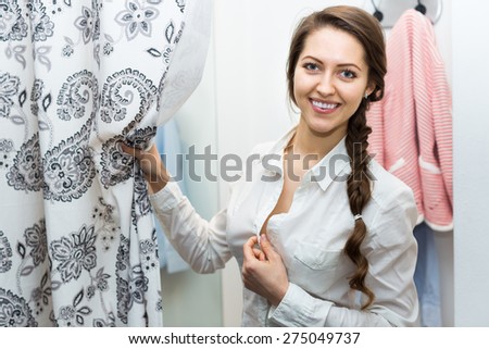 Smiling young attractive woman standing at boutique changing cubicle