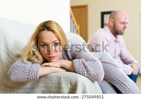 Couple quarrel. Sad guy and wailful girl during quarrel  in living room at home couple having problems at home
