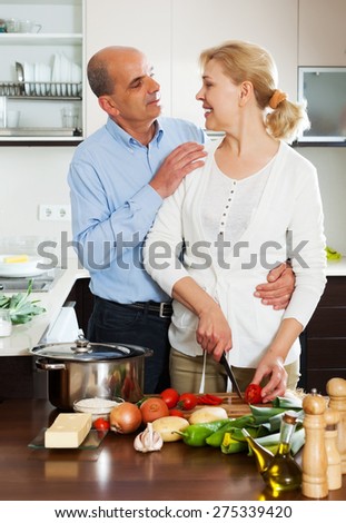Elderly couple cooking salad at home kitchen