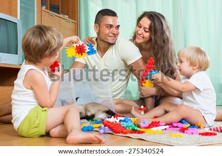 Happy smiling parents and two daughters plays with meccano set in home