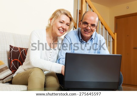 Mature couple with laptop at table at home