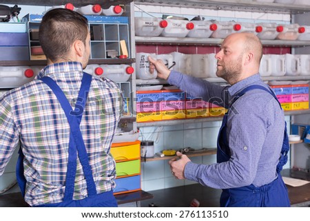 Two workmen standing near storage shelves in auto repair shop