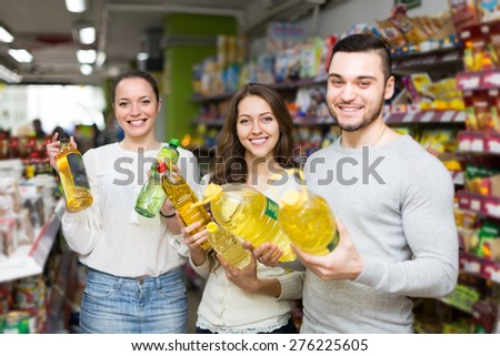 Smiling customers choosing seed-oil in plastic packing at shop. Focus on girl
