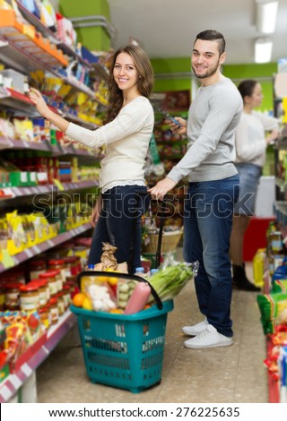 american customers standing near shelves with canned goods at shop