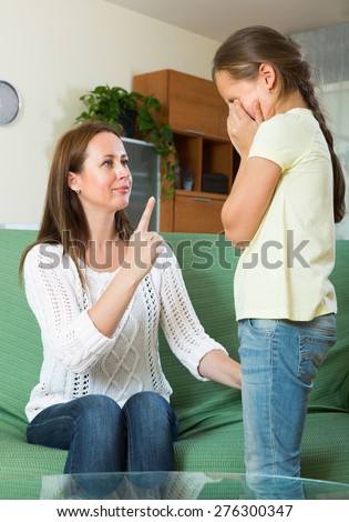 Mother berating  crying schoolgirl at interior