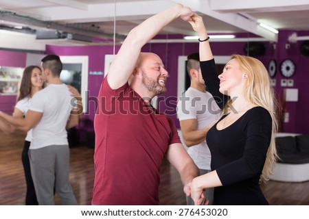Cheerful couples enjoying of partner dance indoor
