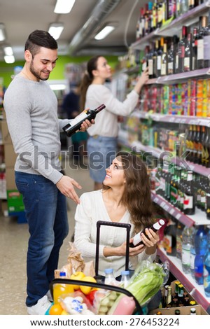 Positive woman and  man  buying beverages for dinner at food shop