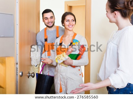 Cheerful woman greeting cleaning service team holding cleansers. Focus on girl