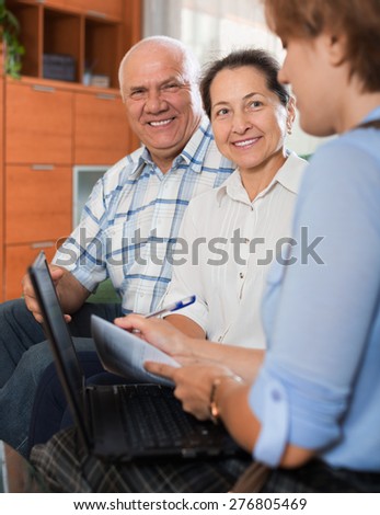 Mature couple answer questions of caseworker with computer in office