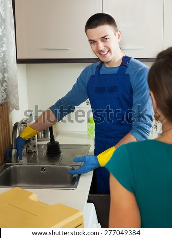 Handsome plumber repairing a running water  for  woman
