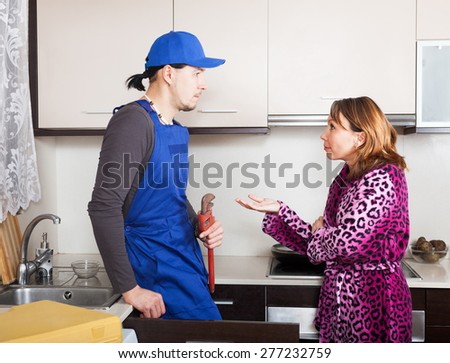Ordinary plumber repairing a kitchen sink for housewife