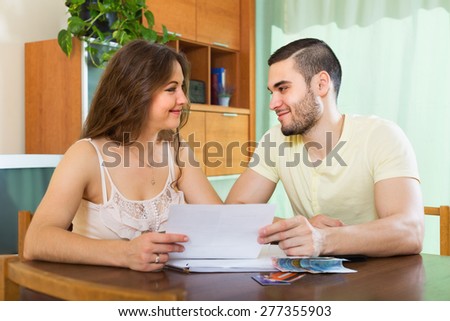 Smiling family with money and financial documents in home interior