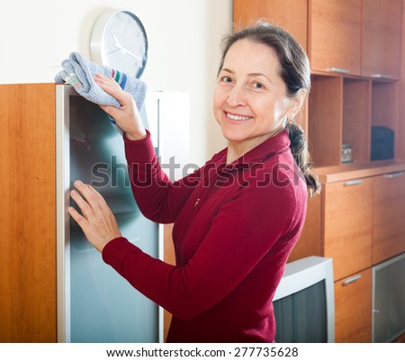 mature woman dusting  furniture at home