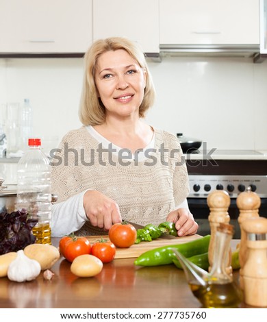 Elderly woman cooking  lunch with veggy at kitchen table