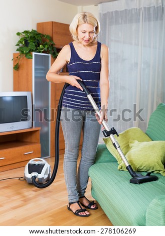 Photo of mature blond woman diligently cleaning apartment