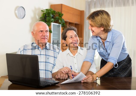 Mature couple filling questionnaire for employee with computer of the bank