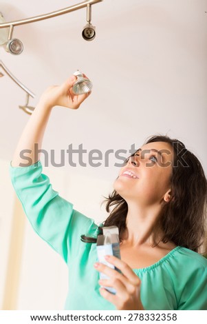 Positive girl changing light bulb at her home