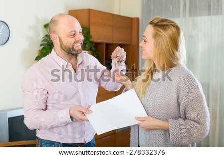 Portrait of happy smiling couple with contract for buying apartment and keys. Focus on woman