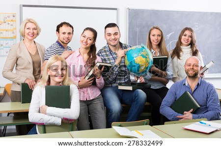 Happy professor and cheerful students posing in classroom at extension courses