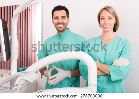 Happy dentist and head nurse standing at room and smiling
