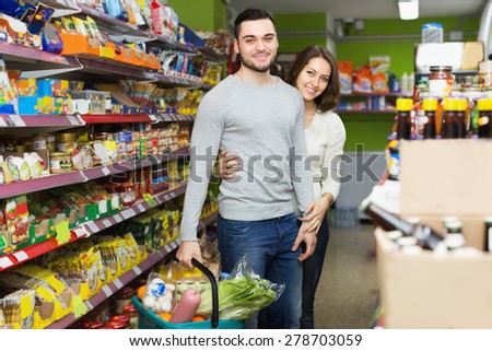 Smiling people standing near shelves with canned goods at shop