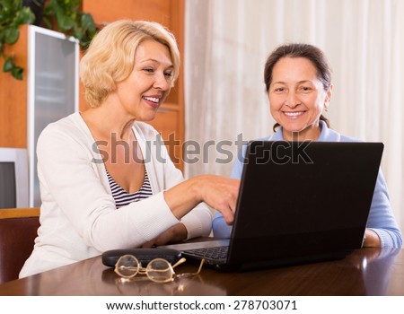 Senior ladies with laptop buying something online. Focus on blonde